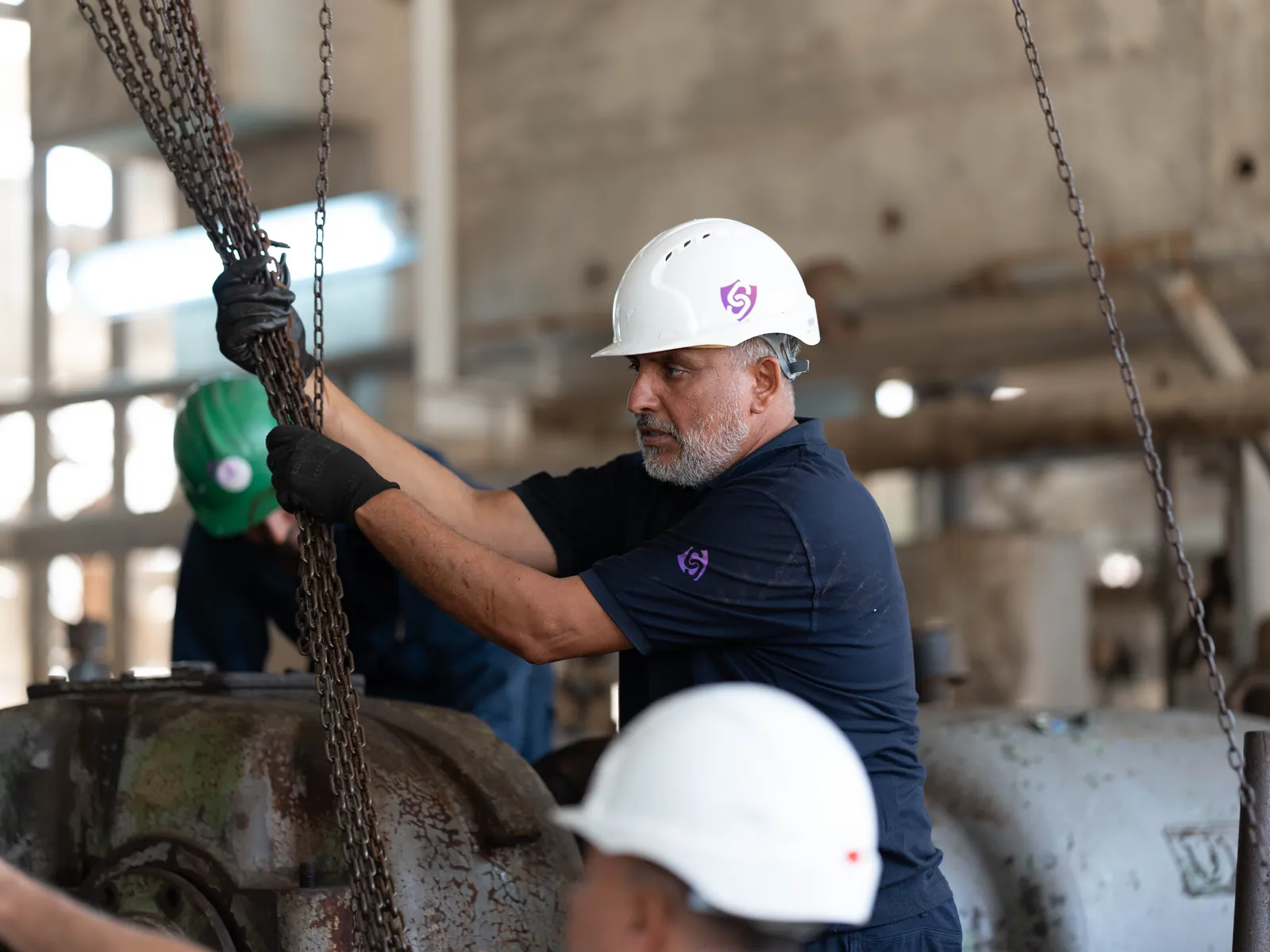 A fitter hauling a chain hoist in a workshop