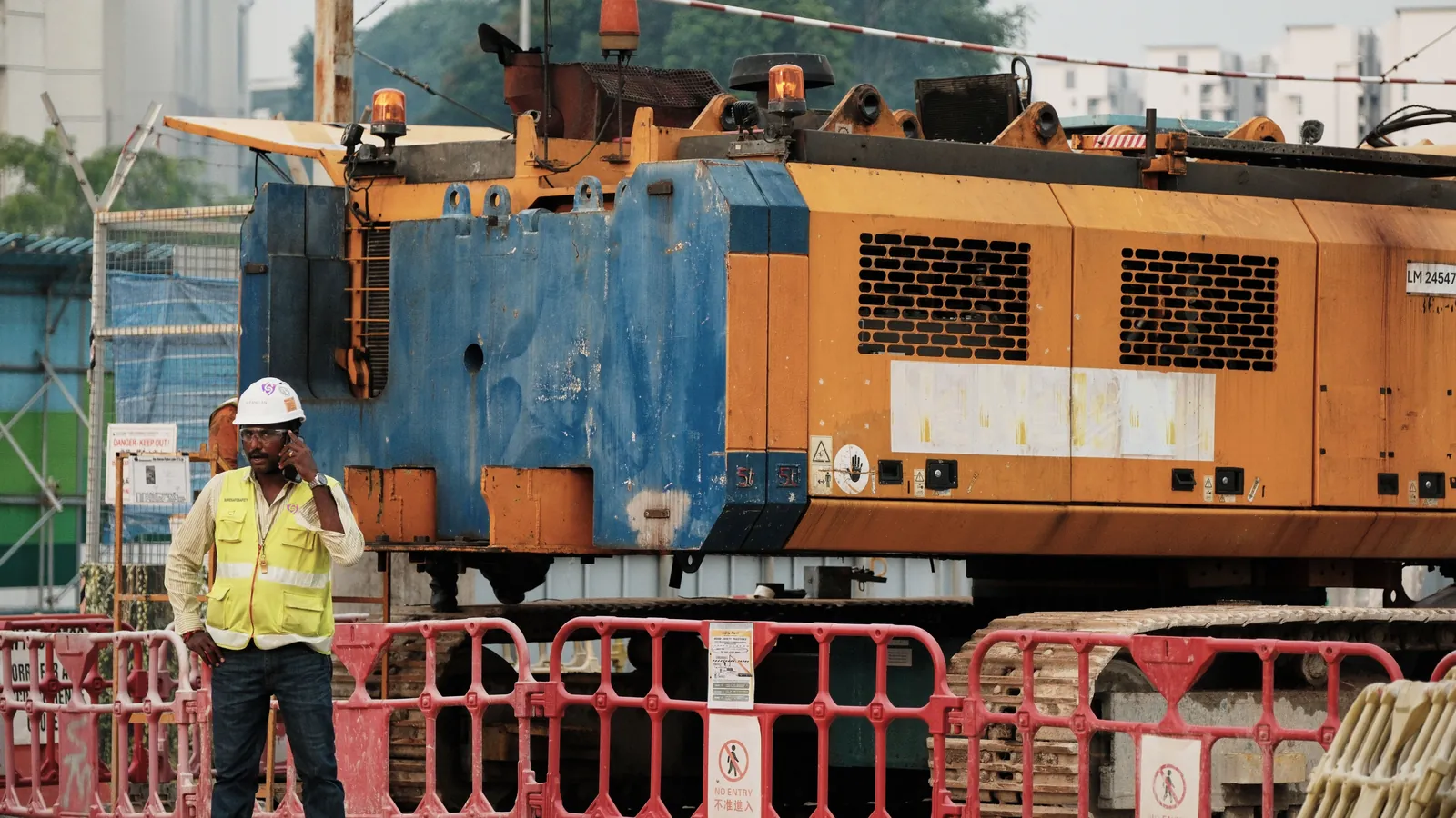 A site supervisor in a hard hat and hi-vis vest on a call